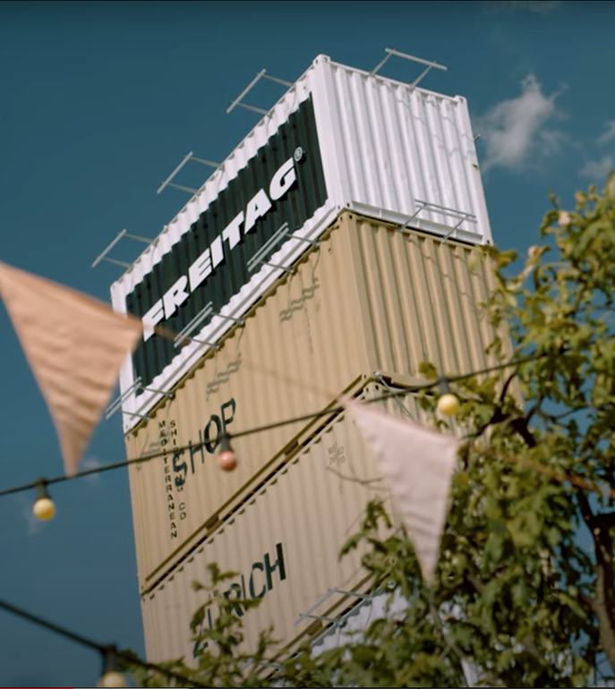 Stacked shipping containers with the logo of Freitag on top (graphic)